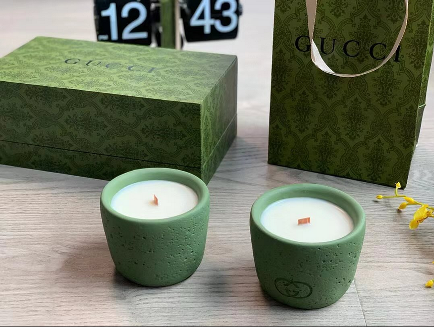 Gucci scented candles in green ceramic containers.