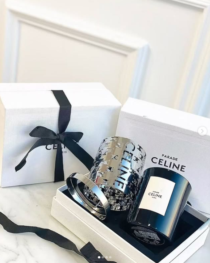 Celine Haute Parfumerie Silence Blanc scented candle gift set. The set features a 240g perfumed candle housed in a black glass container with a black wax wick. It includes a metallic cut-out candle holder designed to mimic the lines of a Celine perfume bo